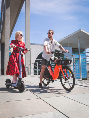 Une femme à trotinette et un homme à vélo électrique Une femme à trotinette et un homme à vélo électrique